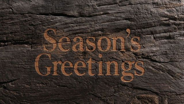 Season's greetings engraved on dark weathered wood plank rustic holiday greeting backdrop
