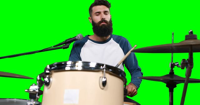Male drumer playing drum against green screen