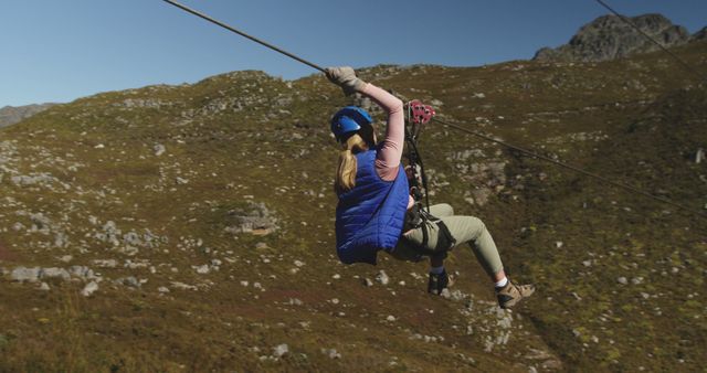 Caucasian woman ziplining with safety belts in mountains, copy space. Ziplining, active lifestyle, safety and nature concept, unaltered.