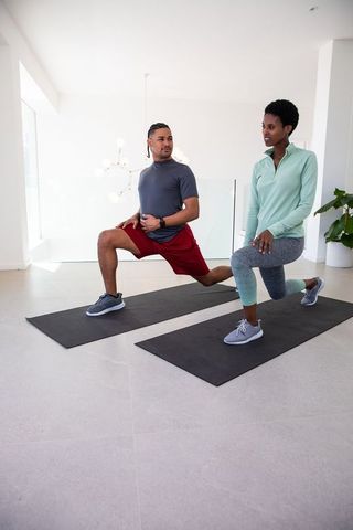 Partners exercising together with forward lunges in home studio