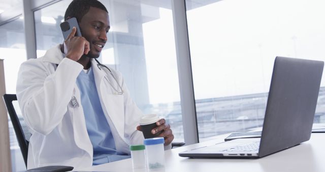 Doctor Holding Coffee Cup Talking on Phone and Using Laptop in Office - Download Free Stock Images Pikwizard.com