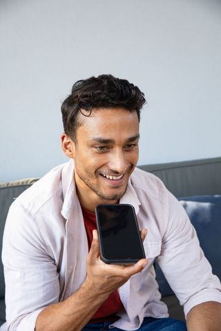 Man engaging with smartphone voice command on sofa