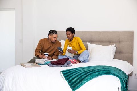 Couple Enjoying Coffee While Sorting Clothes on Bed