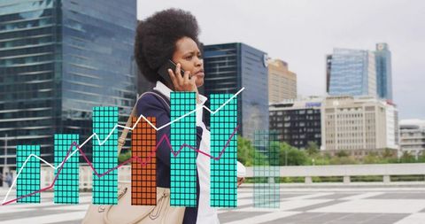 Businesswoman walking and talking on phone with rising data charts overlay in urban plaza