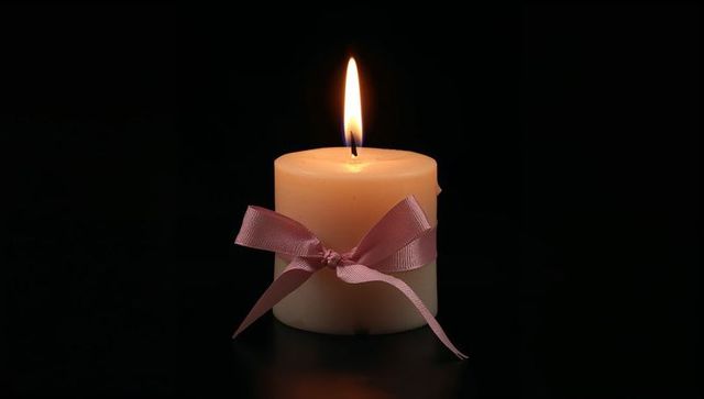 Ivory Pillar Candle with Pink Ribbon on Reflective Surface