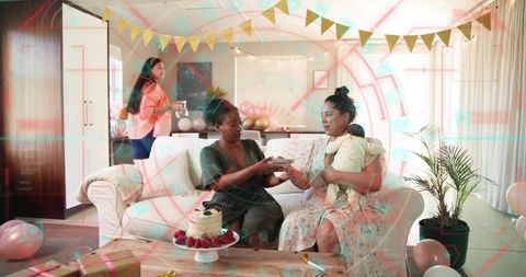 Offering plate to friend holding baby during home celebration with cake, gifts, balloons