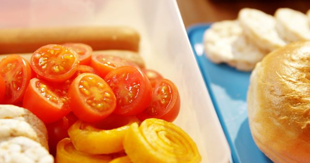 Shows a close-up of a healthy lunchbox containing cherry tomatoes, savory bread rolls, and rice cakes. Ideal for articles or promotions related to wholesome eating habits, nutritious meals, vegetarian diets, meal prepping, and school or workplace lunch ideas.
