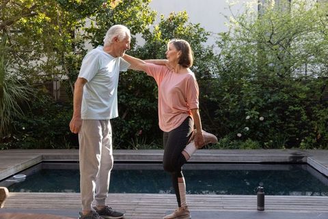Senior Couple Stretching Together by Outdoor Pool