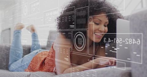 Smiling african american woman studying on laptop with futuristic hud dashboards