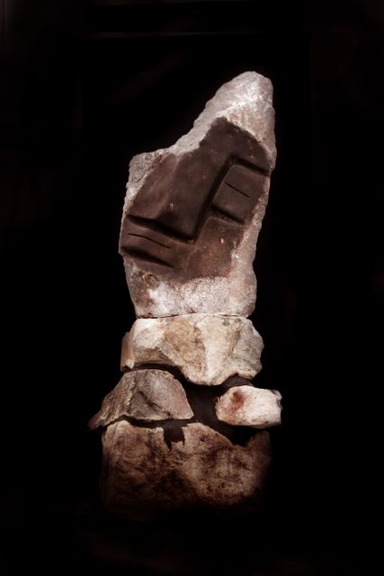 Image shows a tall, stacked formation of variously shaped rocks under striking lighting against a black background. Suitable for illustrating concepts related to nature, geological formations, sculpture, minimalism, and art. Ideal for use in educational materials, geological studies, and artistic publications.