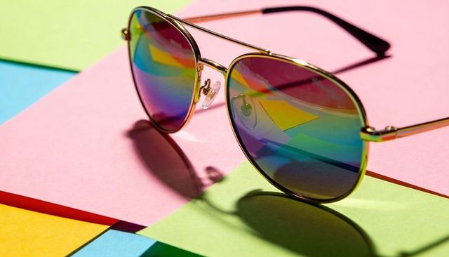 Gold Aviator Sunglasses Showing Rainbow Mirrored Lenses on Pastel Colorblock Backdrop