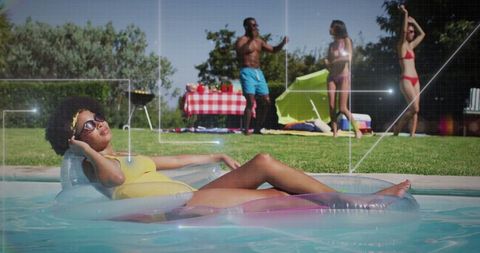 Woman relaxing on inflatable raft in sunny backyard pool gathering