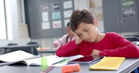 focused boy solving math problem in classroom with books and tablet - Download Free Stock Images Pikwizard.com