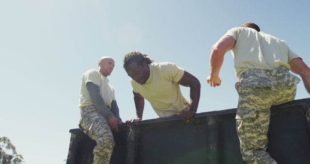 Group of soldiers working together to overcome an obstacle during an outdoor military training session. This image highlights cooperation, endurance, and physical fitness. Ideal for articles, websites, and advertisements related to military training, teamwork, and physical fitness programs.