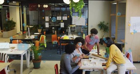 Four Designers Collaborating in Modern Open-Plan Office