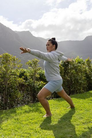 Practicing warrior lunge on mountain lawn for outdoor wellness and mindful balance