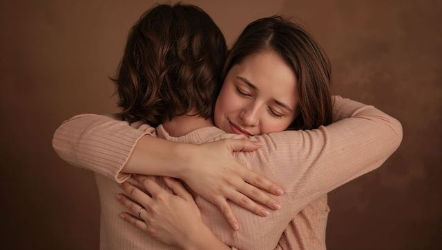 Two women embracing in pastel ribbed tops conveying tenderness and warmth