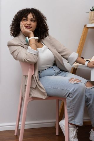 Contemplating young woman wearing beige blazer and smartwatch in minimalist home workspace