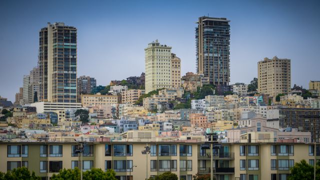 Panoramic view of modern urban skyline featuring tall skyscrapers and diverse residential buildings. Ideal for real estate themes, urban planning presentations, and city tourism promotions.