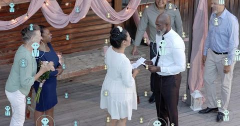 Exchanging vows on rustic wooden deck during intimate outdoor wedding ceremony with family