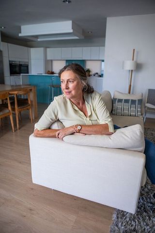 Senior Woman Relaxing in Contemporary Living Room with Teal Kitchen