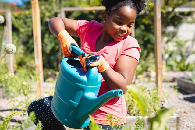 Young African American girl enjoying gardening in a backyard garden, wearing gloves and using a watering can. Perfect for content related to childhood activities, outdoor hobbies, environmental education, and family lifestyle.
