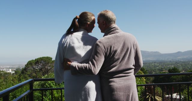 Rear view of caucasian senior couple in bathrobes embracing each other in the balcony at home. staying at home in self isolation in quarantine lockdown