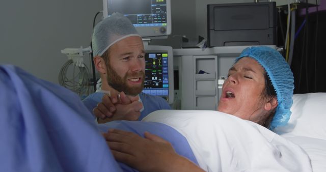 Front view of Caucasian man comforting pregnant woman during labor in operation theater at hospital. He is holding her hand 4k