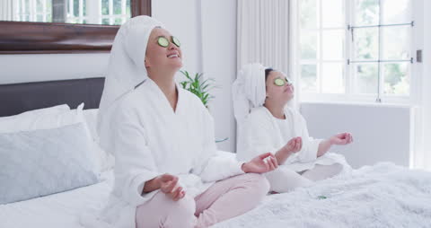 Mother and Daughter Relaxing with Cucumber Masks and Meditation