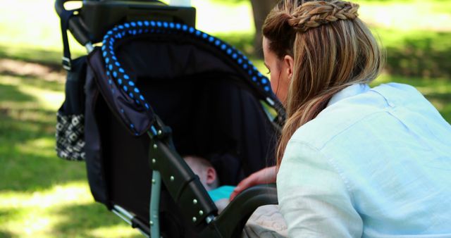 Mother Gently Attending to Her Baby in Stroller Outdoors - Download Free Stock Images Pikwizard.com