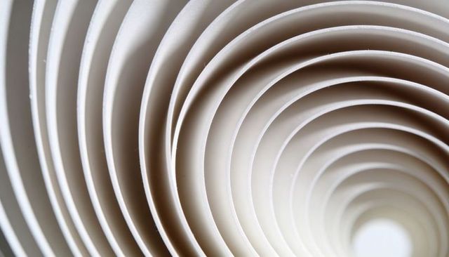 Spiraling concentric paper rings forming tunnel with soft shadows and textured surface