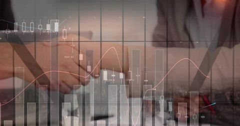 Shaking hands over financial charts signaling partnership negotiation and investment