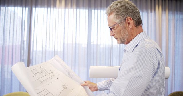 Senior Architect Reviewing Architectural Blueprints in Office - Download Free Stock Images Pikwizard.com