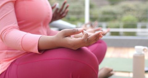 African American Women Meditating on Balcony Yoga Mats in Pink Activewear Mindfulness Session