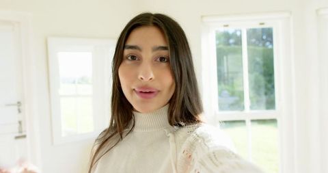 Serene Indian Woman in Minimalist Sunlit Room with Large Windows