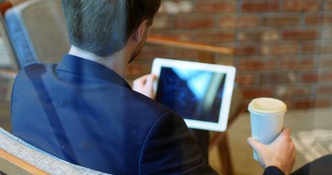 Businessman Engaged with Digital Tablet in Modern Cafe Setting