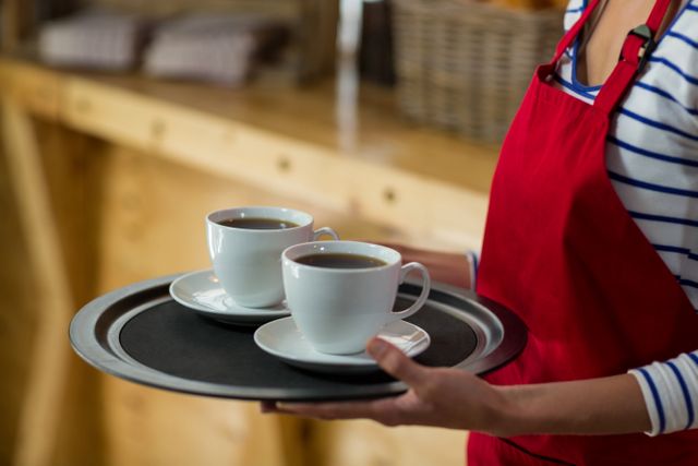 Mid-section of waitress standing with cup of coffee in cafÃ©