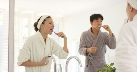 Couple brushing teeth together in bright modern bathroom morning routine mirror reflection