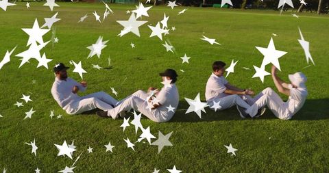 Cricket teammates sitting linking hands on grass with star overlays at golden hour