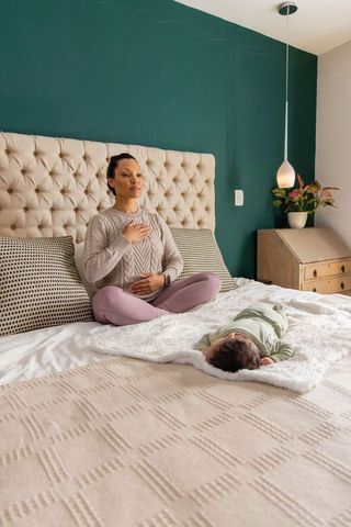 Mother practicing mindful breathing with infant on cozy bed while bonding