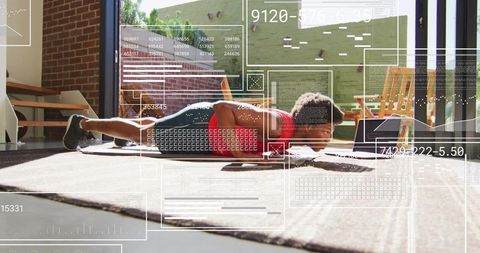 Man performing floor workout at home with laptop and digital hud fitness data overlay