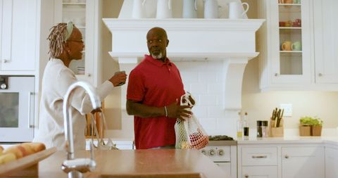 Senior African American Couple Unpacking Groceries in Home Kitchen