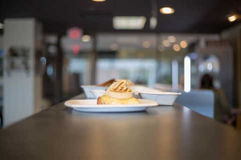 Breakfast sandwich on plate sitting on cafe counter with soft bokeh background