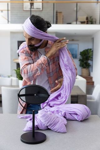 Man wrapping lilac turban at home in modern kitchen