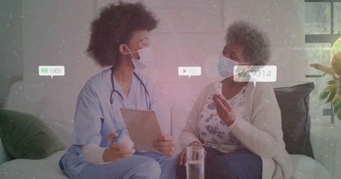 Nurse consulting senior on medication management in home while both wearing masks