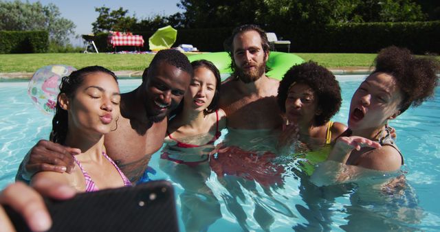 Diverse group of friends having fun taking a selfie in swimming pool. hanging out and relaxing outdoors in summer.