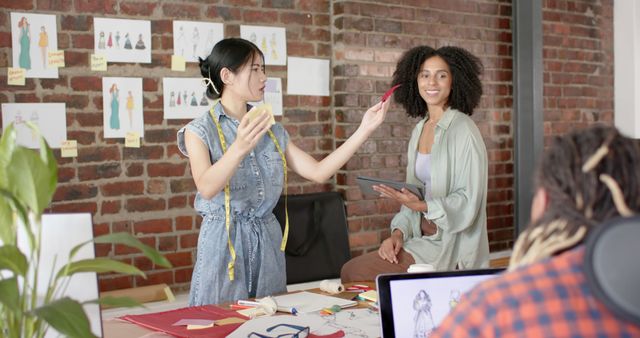 Creative Professional Asian Woman Presents Fashion Designs to Multiracial Team - Download Free Stock Images Pikwizard.com