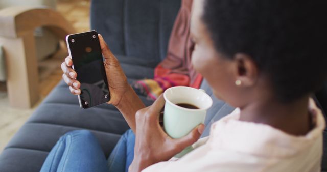 Young Woman Holding Smartphone and Coffee Cup Relaxing on Couch - Download Free Stock Images Pikwizard.com