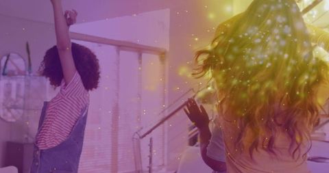 Three friends dancing in cozy living room with golden glow and celebration energy