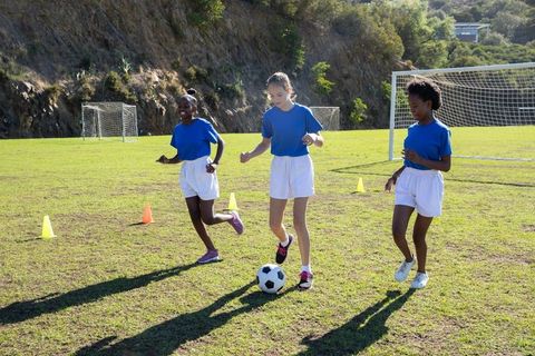 Teen girls training soccer skills on sunny field